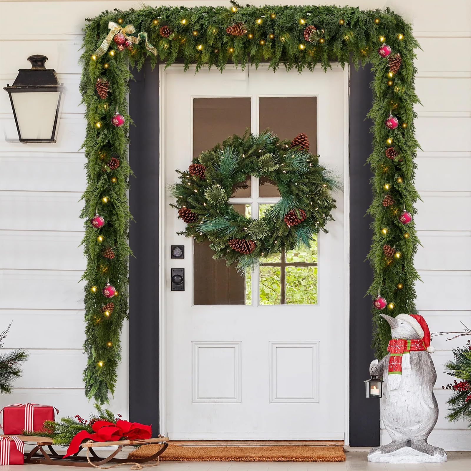 Decorative Christmas garland with lights and ornaments on a door frame, featuring a wreath and penguin statue.